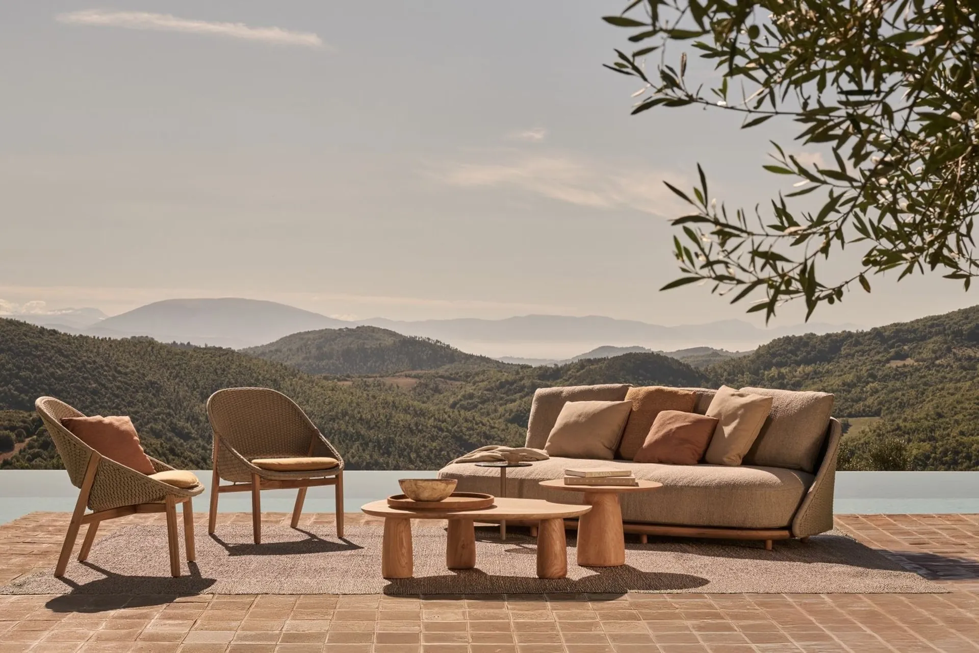 Tribù Elio sofa, lounge chairs and low tables on a terrace above a valley