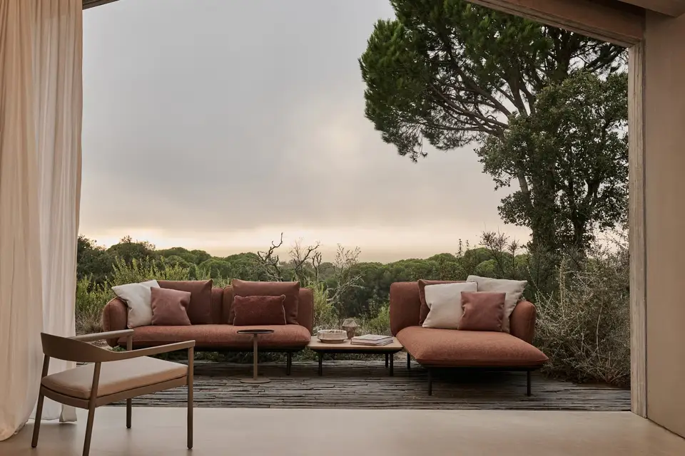 Tribù Illum lounge chair with terracotta sofas in a gabled pavilion open to pine trees