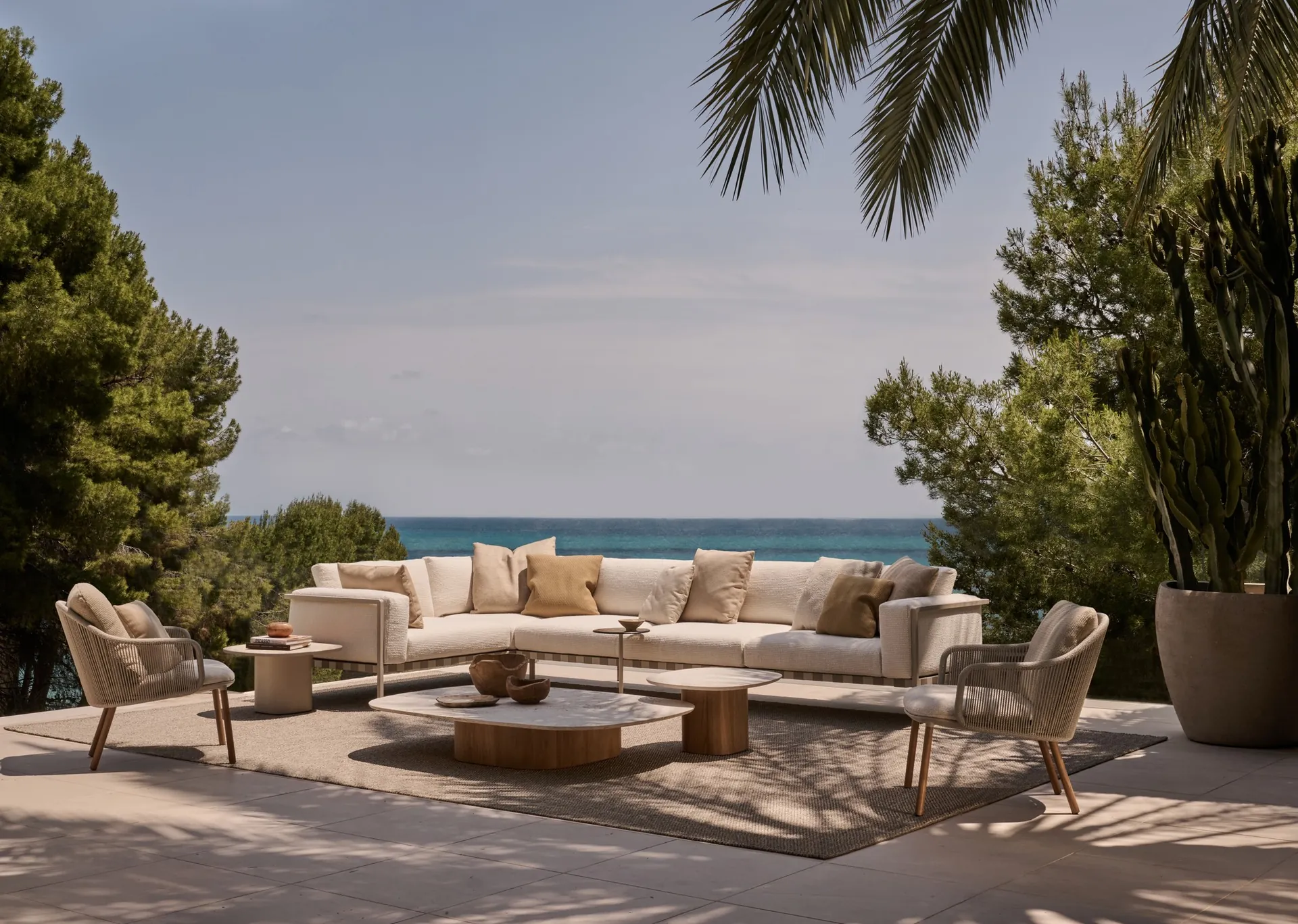 Tribù Natal Alu sofa with lounge chairs and low tables on a terrace above the sea