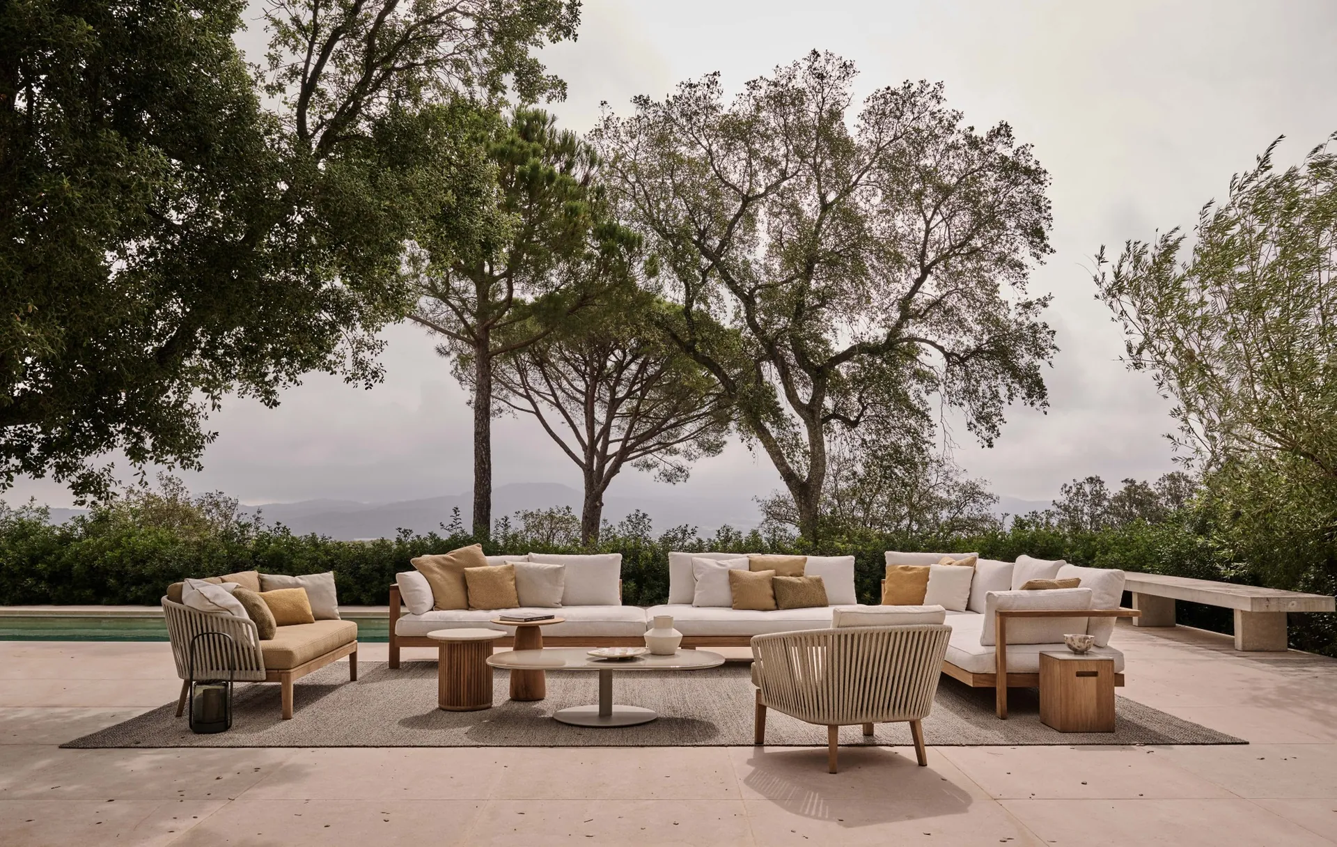 Tribù Pure sofas and armchairs around low tables on a terrace under pines