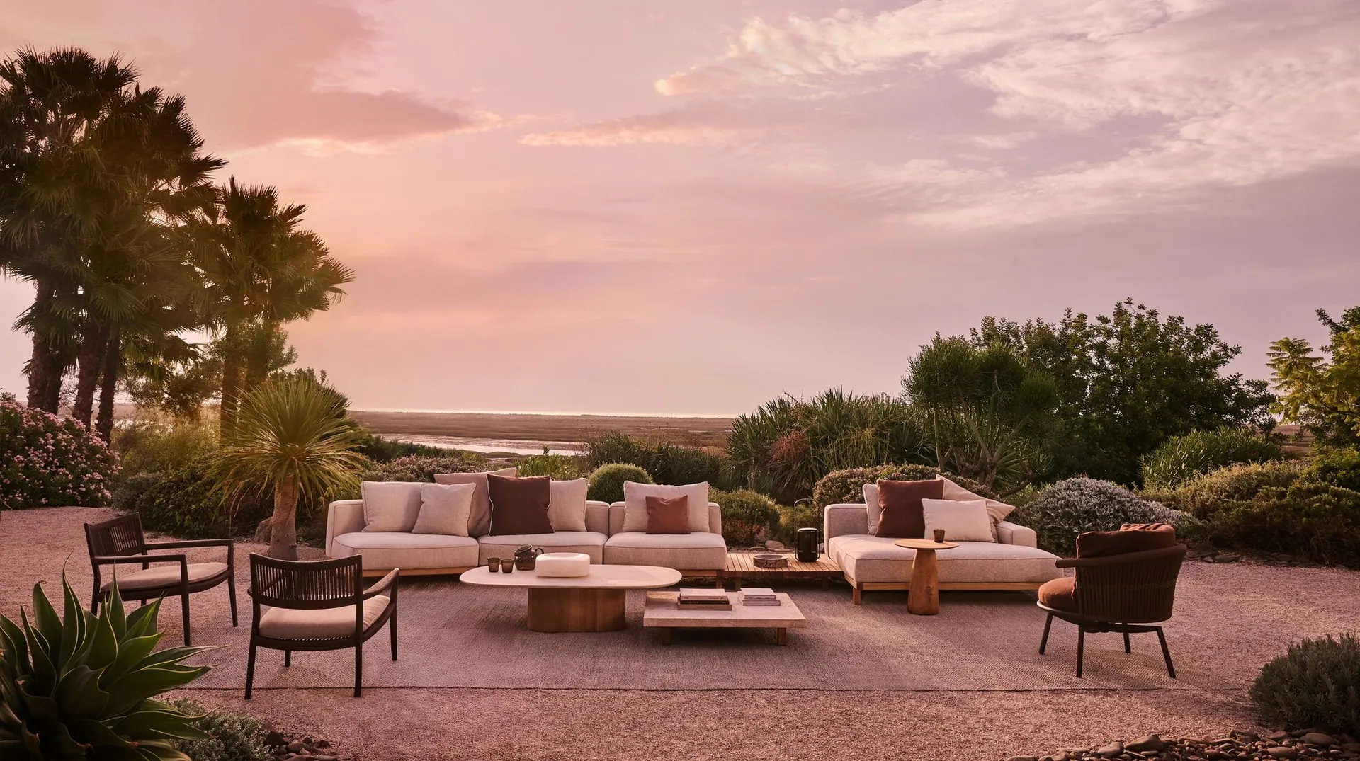 Tribù Vis à Vis teak sofa group with low tables on a terrace at sunset