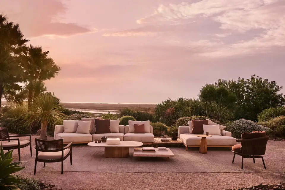 Tribù Vis à Vis teak sofa group with low tables on a terrace at sunset